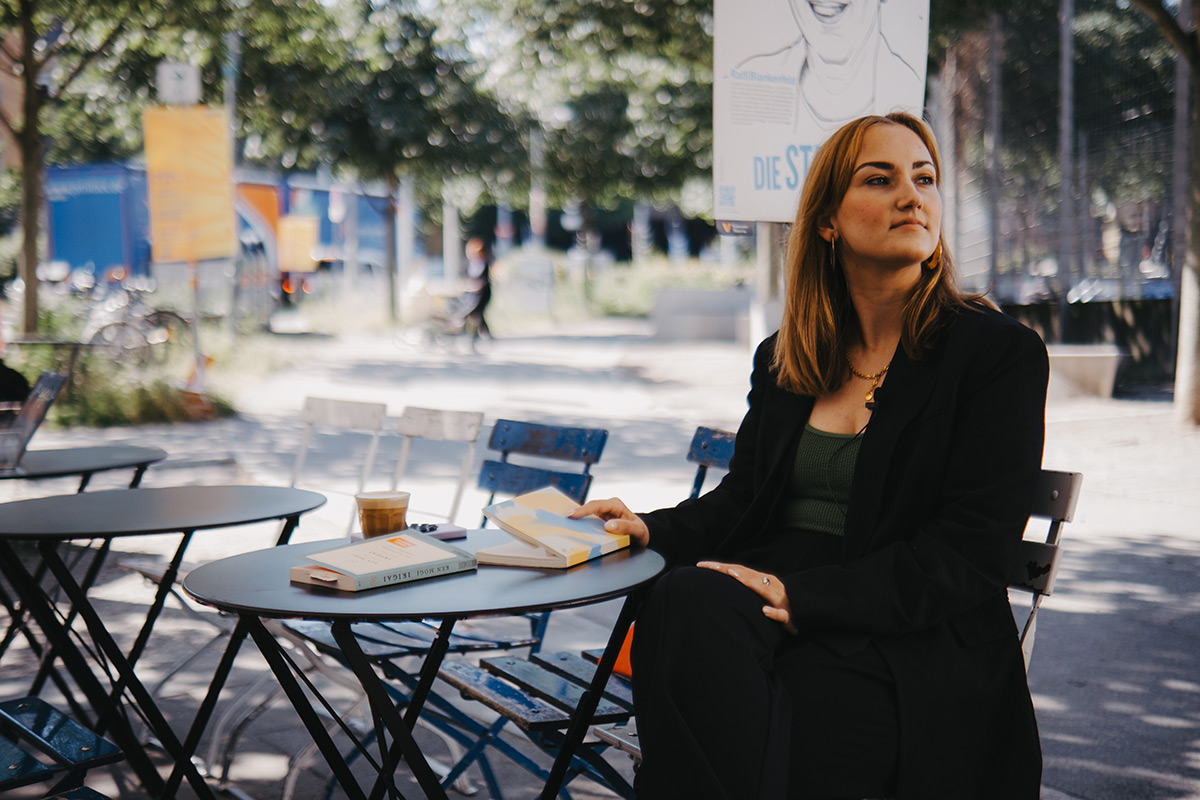 Denise sitzt vor der Café-Bar Condesa und hat ein Buch in der Hand