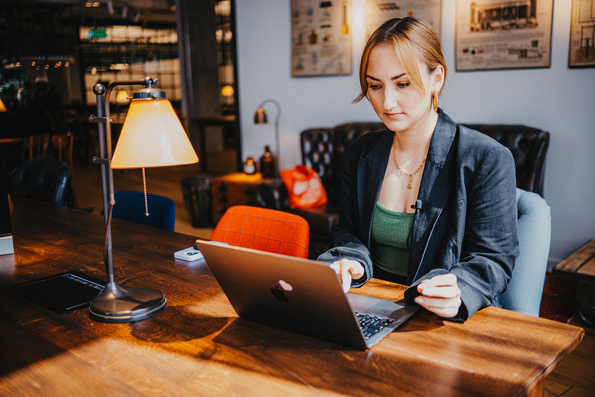 Denise sitzt in einem Shared Office und arbeitet konzentriert an ihrem Laptop