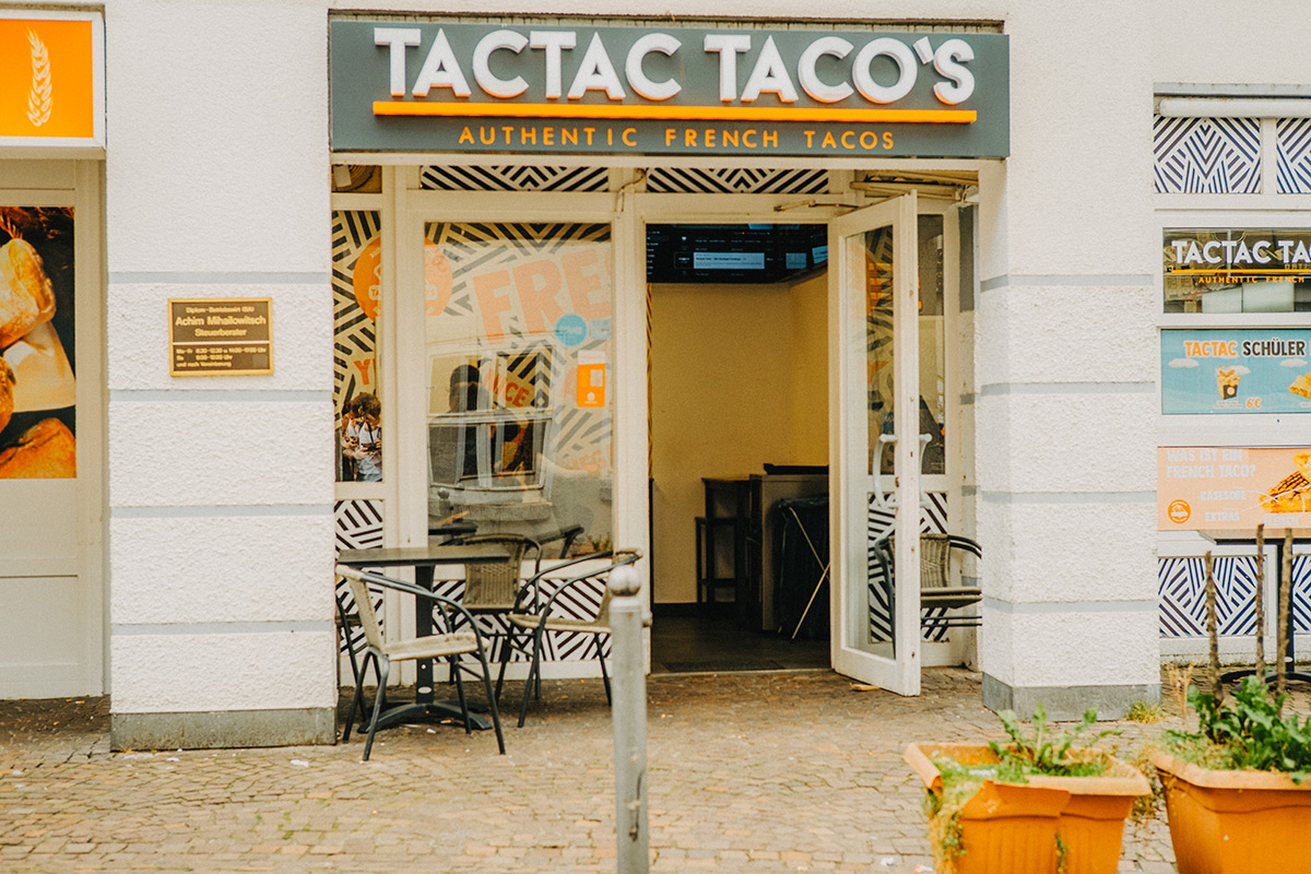 Vor dem Eingang des Tac Taco's steht ein Tisch mit Stühlen zum essen