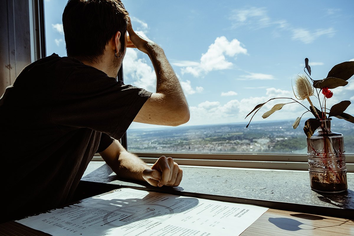 Ein Mann schaut aus dem Fester des Cafés Leonhardts im Fernsehturm. Er blickt über ganz Stuttgart.