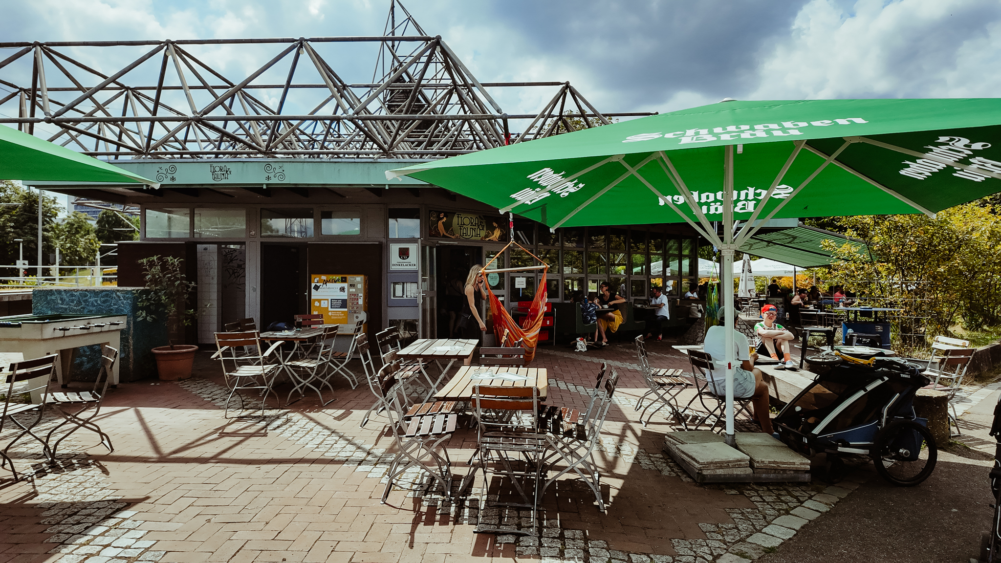 Biergarten Flora und Fauna mit Sitzgelegenheiten und Sonnenschirmern.