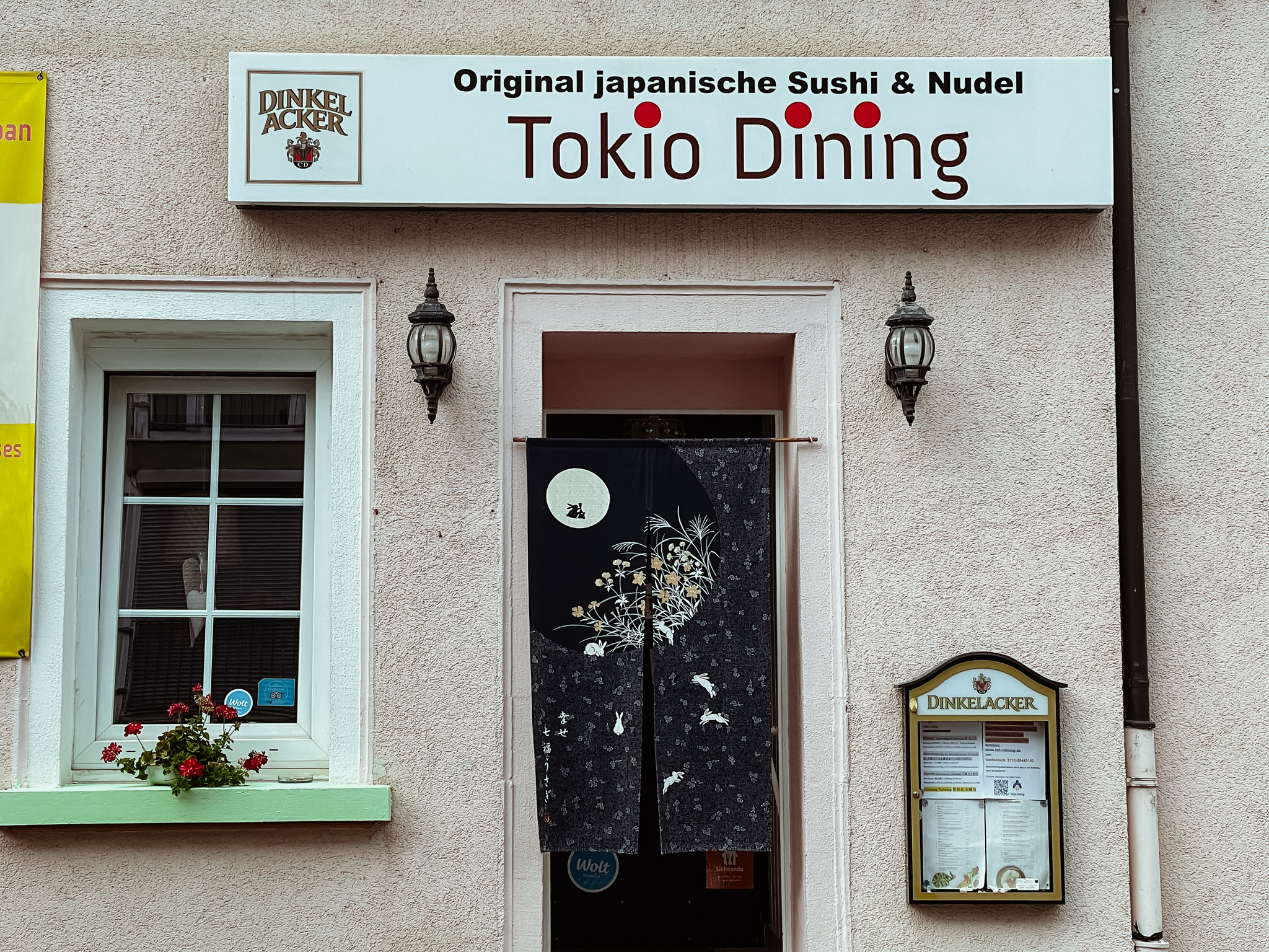 Eingangsbereich zu einem Restaurant vor welchem ein japanisches Tuch hängt.