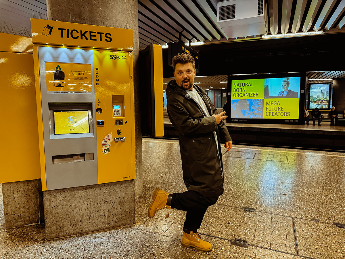 Bartek steht an der Haltestelle Charlottenplatz und posiert vor dem Fahrkartenautomat