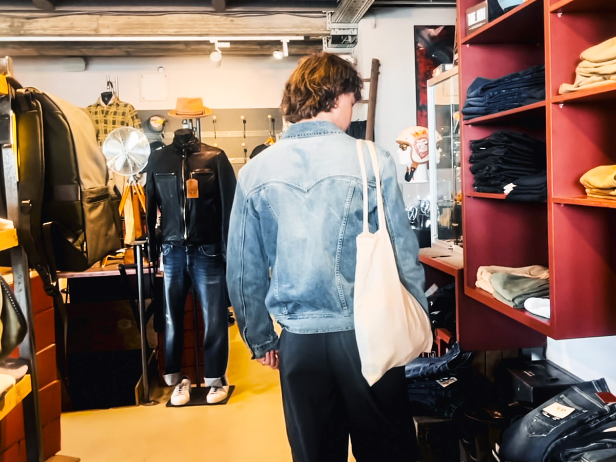 Rückansicht eines jungen Mannes mit brauner Kurzhaarfrisur, der durch die Regale des Herrenmodeladens Kings & Bastards in Leinfelden unweit der Haltestelle Neuer Markt stöbert