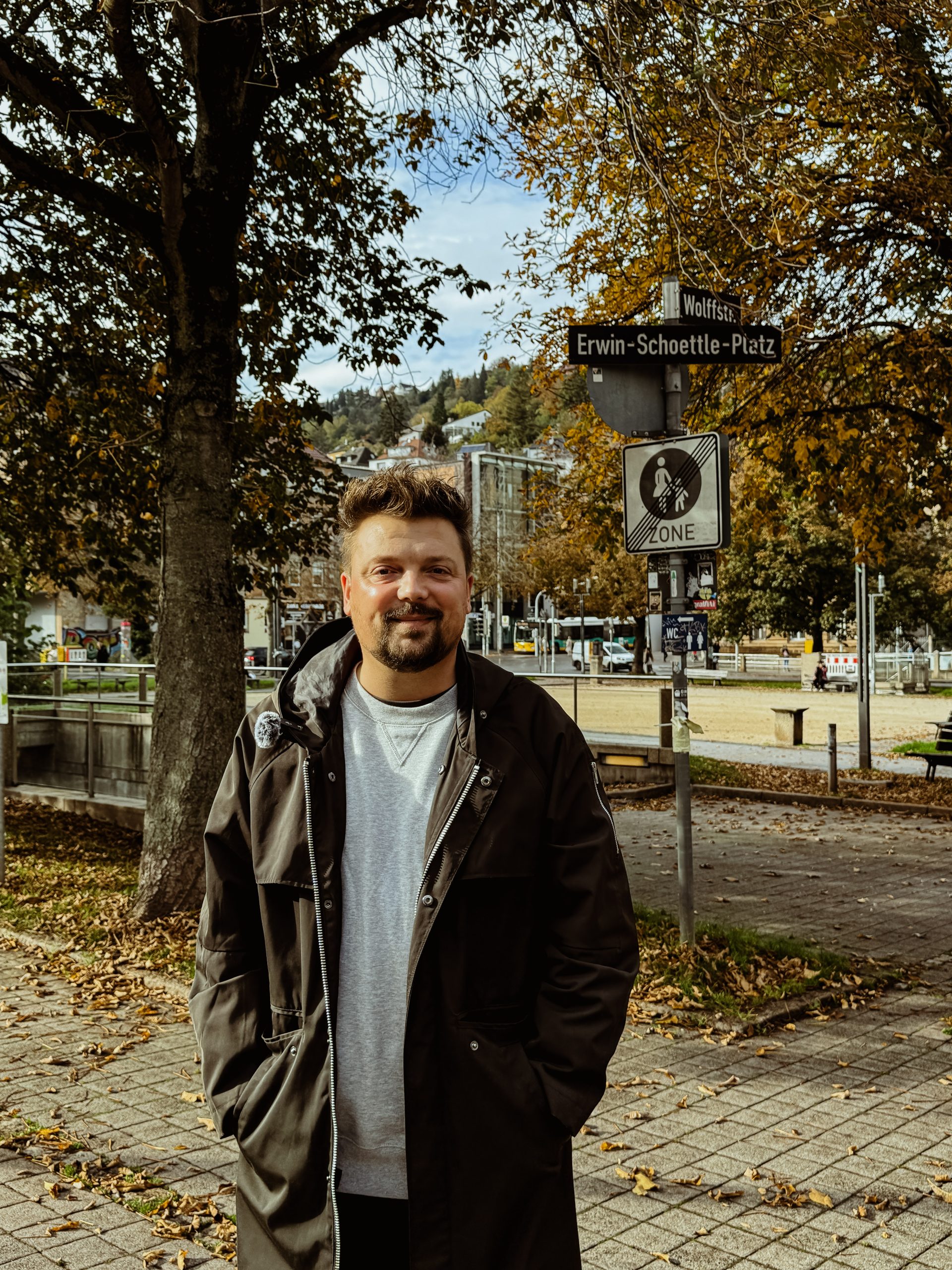 Bartek steht vor dem Straßenschild am Erwin-Schöttle-Platz